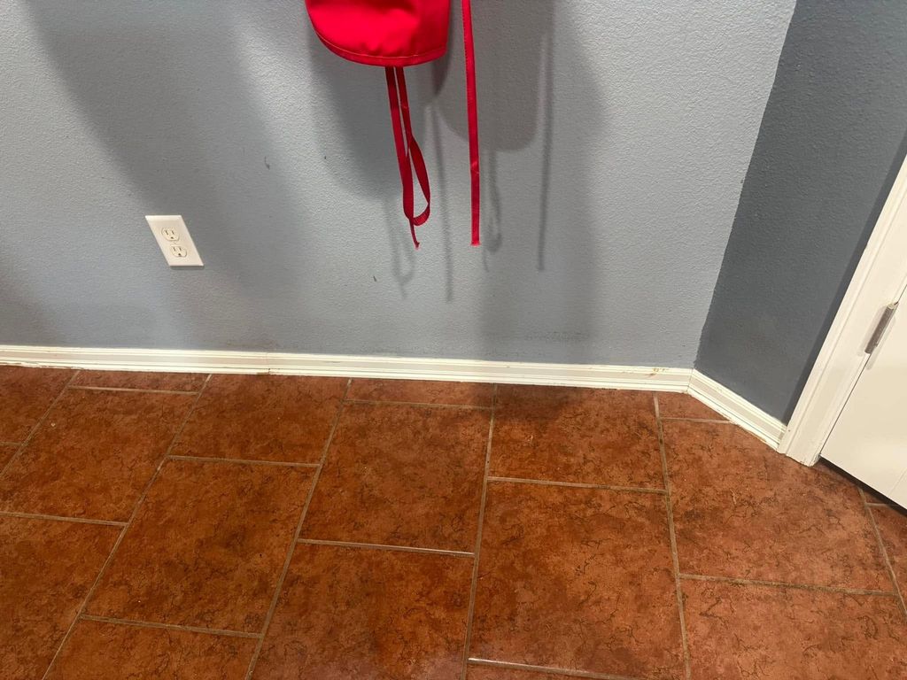 White baseboards after cleaning beside a brown tile floor