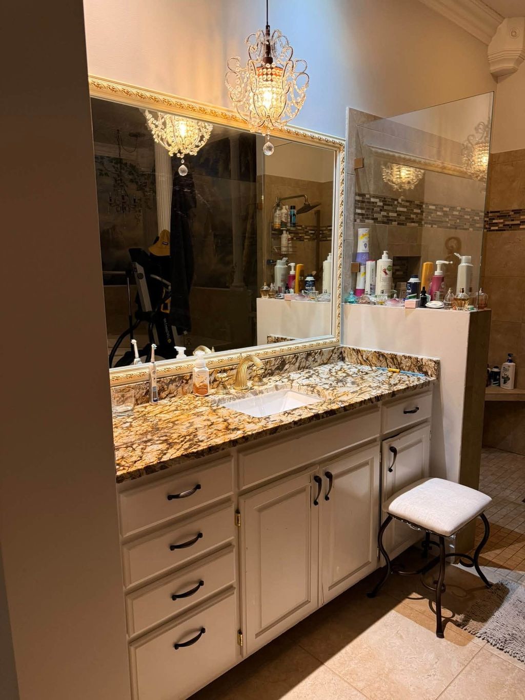 Clean bathroom vanity with granite counter, framed mirror and crystal chandelier