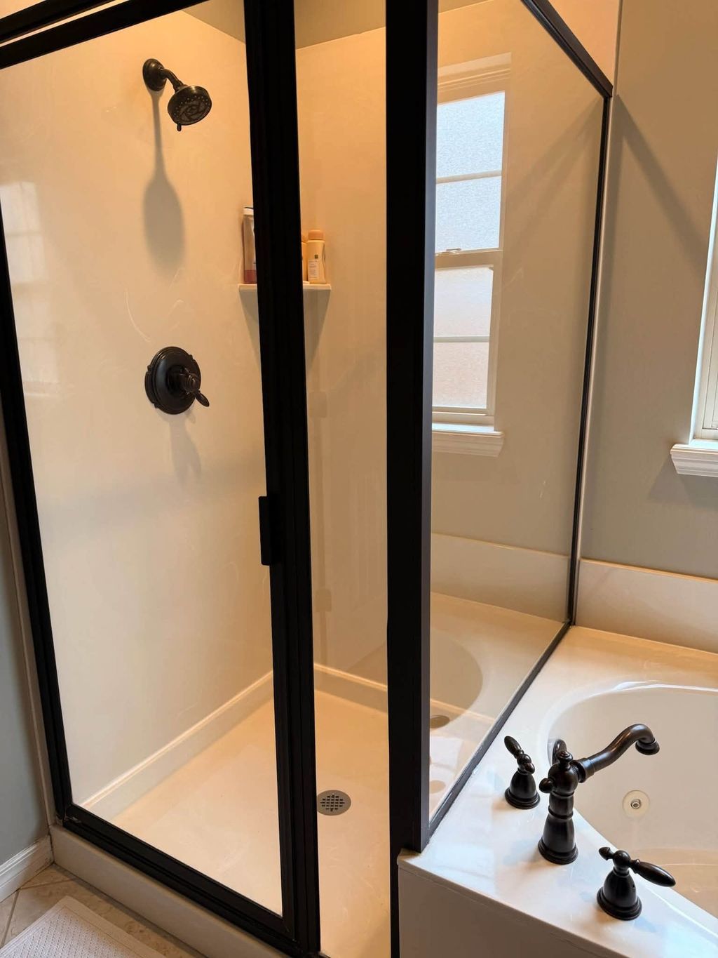 Clean glass shower enclosure beside a white bathtub
