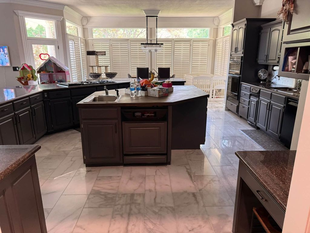 Kitchen with a large island, dark cabinets and polished marble tile floor