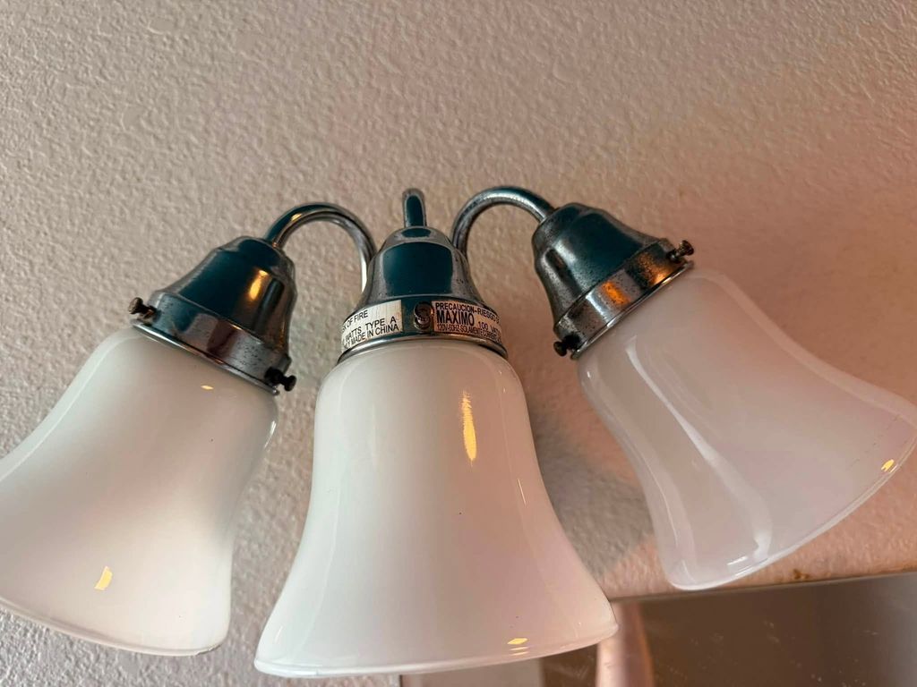 Three-light bathroom fixture after cleaning with polished metal shades