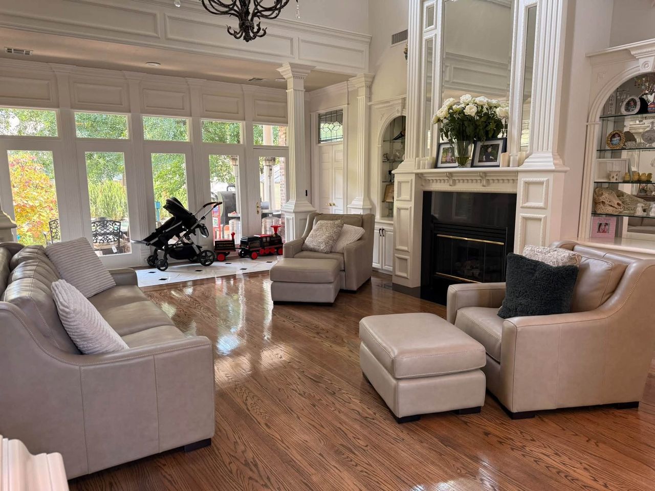 Two-story living room with a fireplace, leather seating and polished hardwood floors