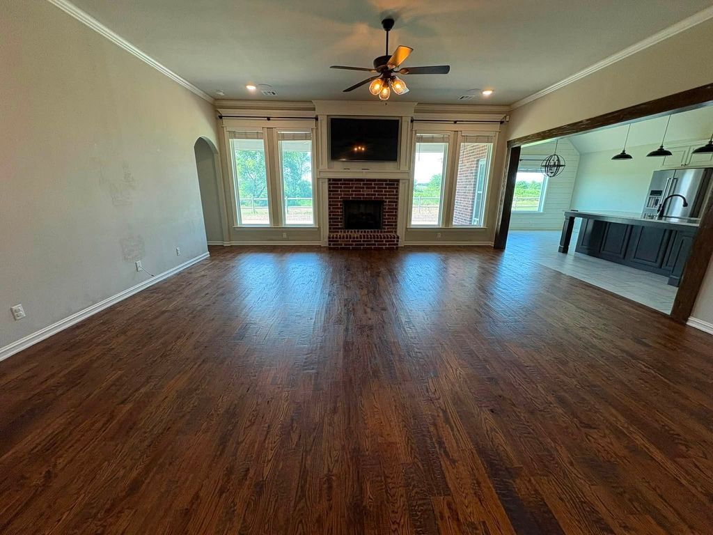 Empty living room with polished hardwood floors and a brick fireplace